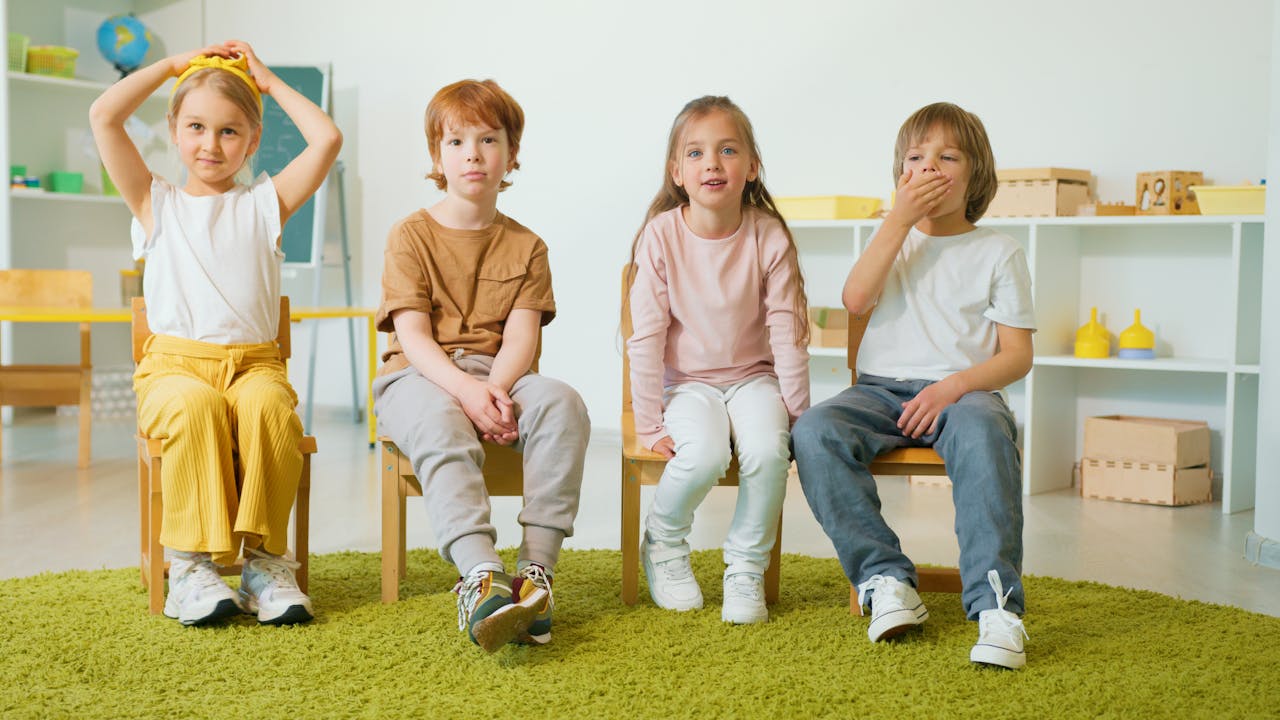The Art of Drawing Readers In: Your attractive post title goes here Group of children sitting on chairs in a classroom, smiling and engaged.